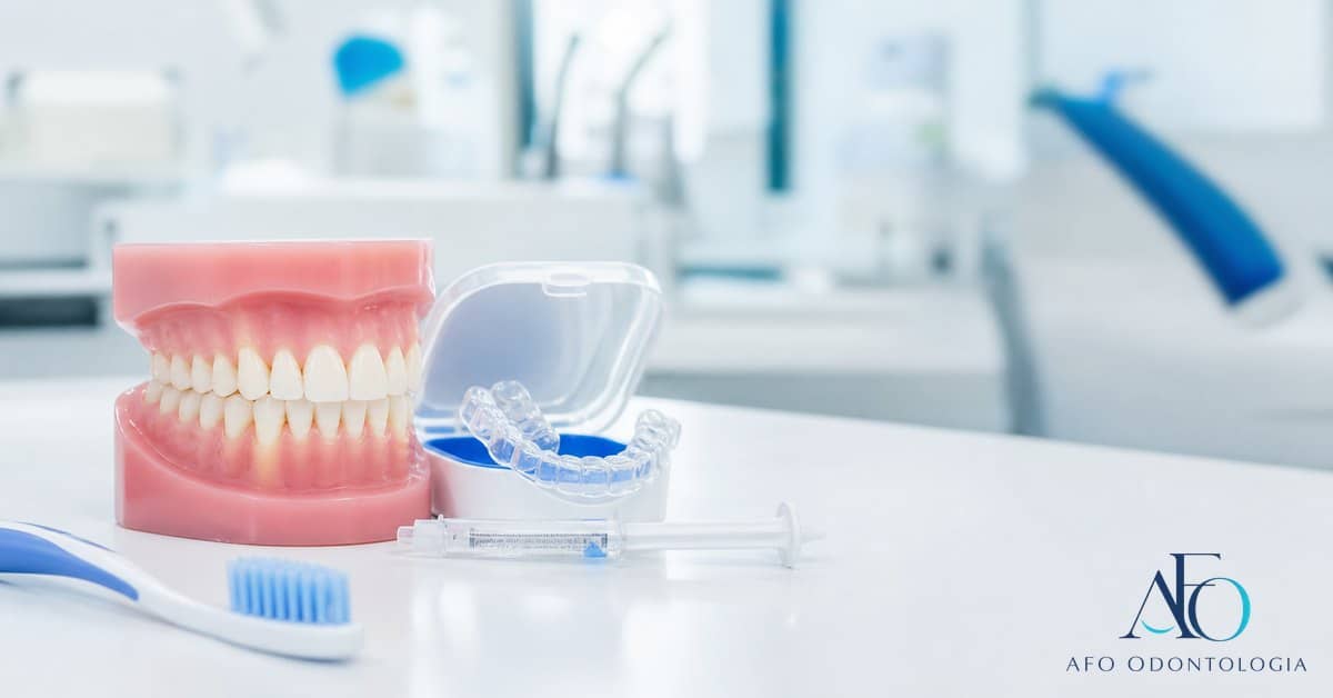 Paciente sorrindo em consulta de clareamento com detalhes azuis e logo novo da AFO