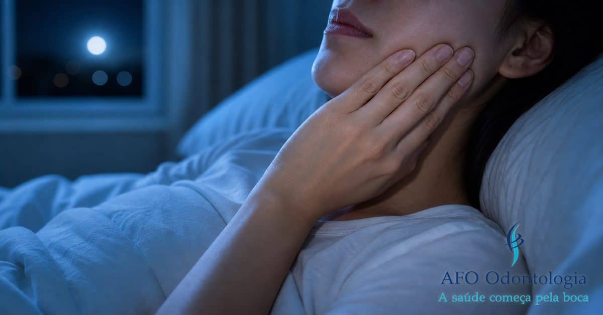 Pessoa deitada na cama à noite com a mão no maxilar sentindo dor de dente