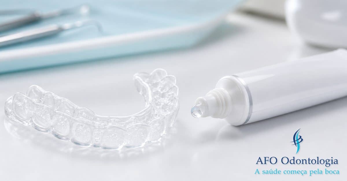 Moldeira de clareamento dental com gel branqueador ao lado de tubo de gel profissional sobre superfície branca